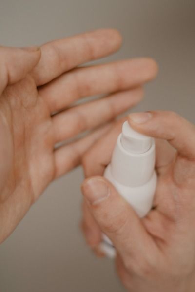 person holding bottle - Acne Serums