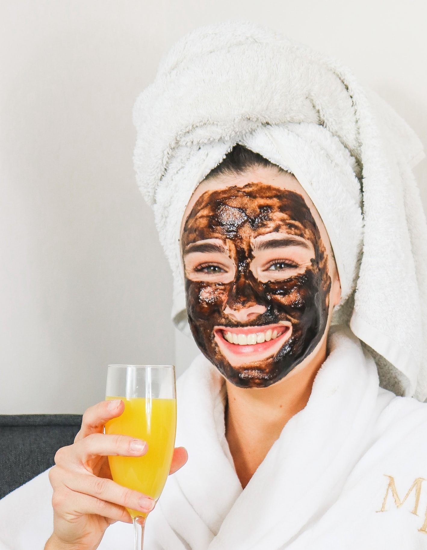 man in white bathrobe holding clear drinking glass with yellow liquid - best acne treatment