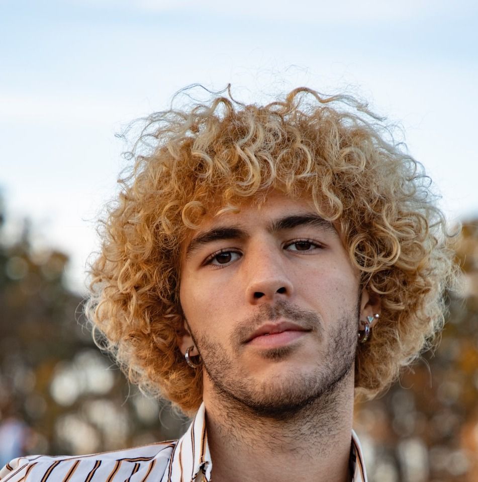 a man with curly hair wearing a striped shirt