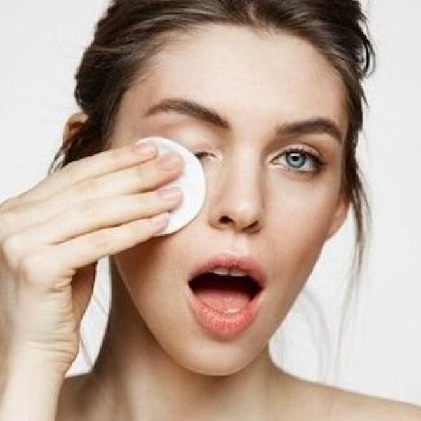 girl with cotton wiping off her eye on white background