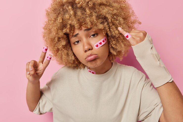 dissatisfied girl with curly red hair wearing a white t-shirt and a pink photo background