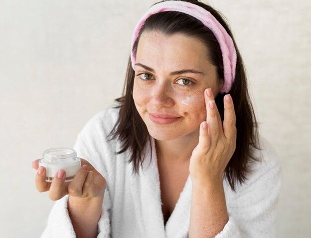 girl with white towelling gown and moisturizer in her hand - Hyaluronic Acid