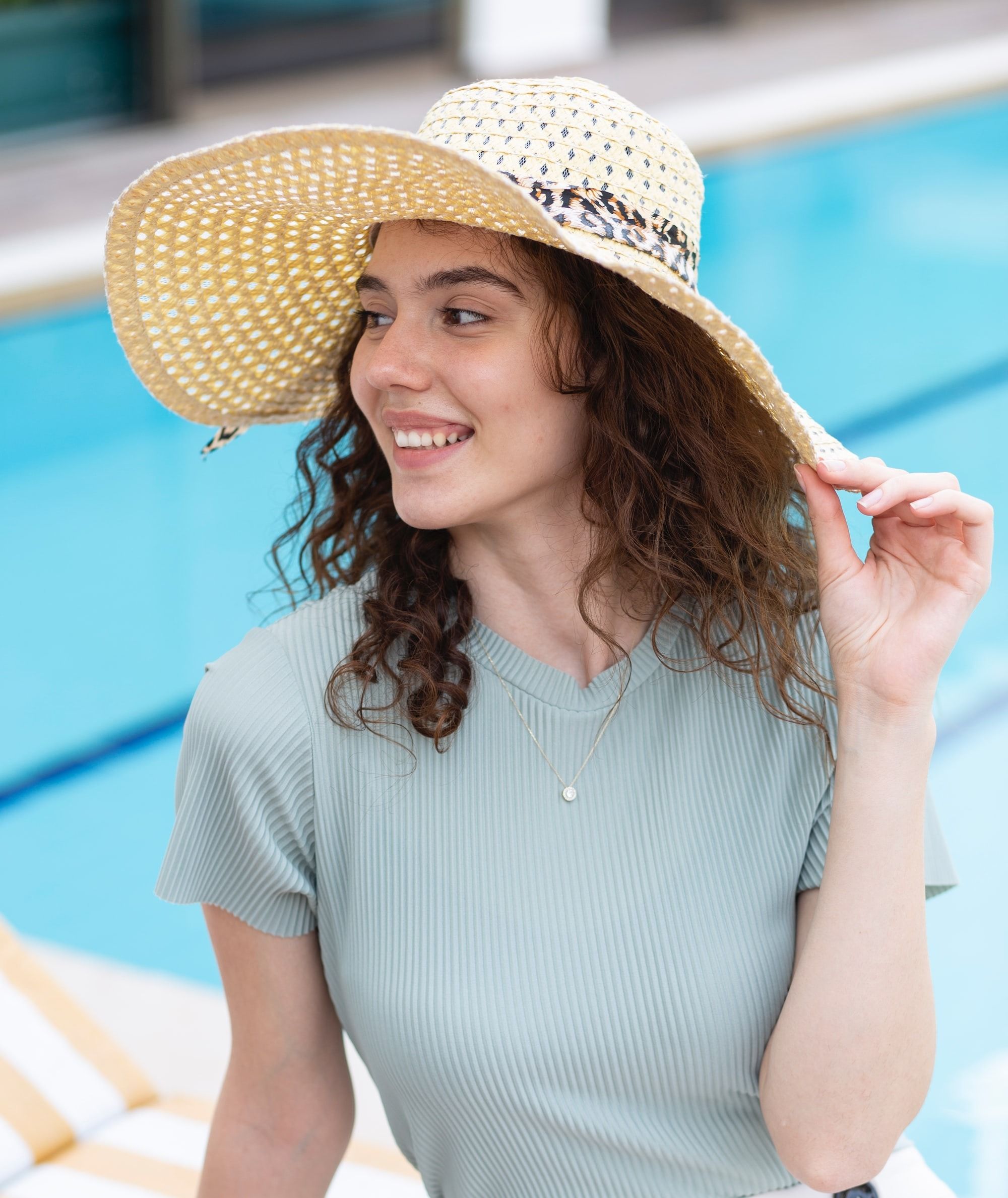 woman in white and blue striped dress wearing brown straw hat best foundations for acne prone skin