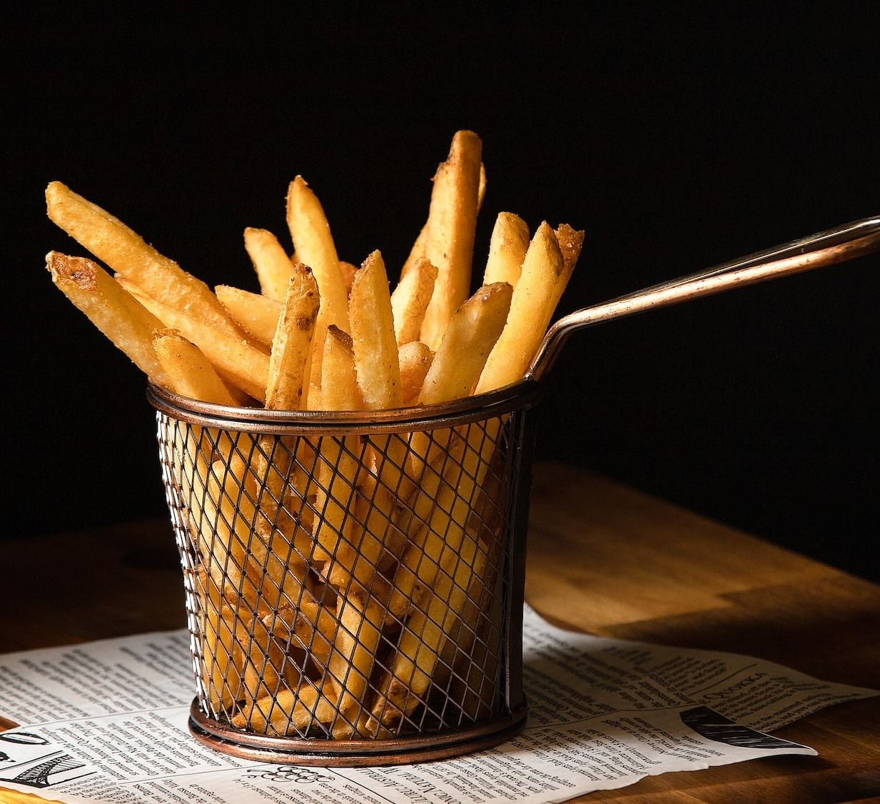 a basket of french fries sitting on top of a wooden table