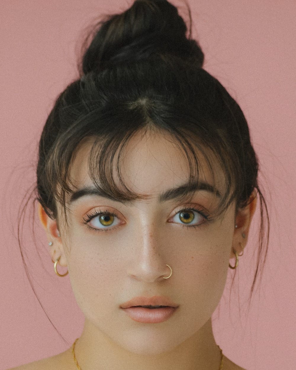 woman staring directly at camera near pink wall