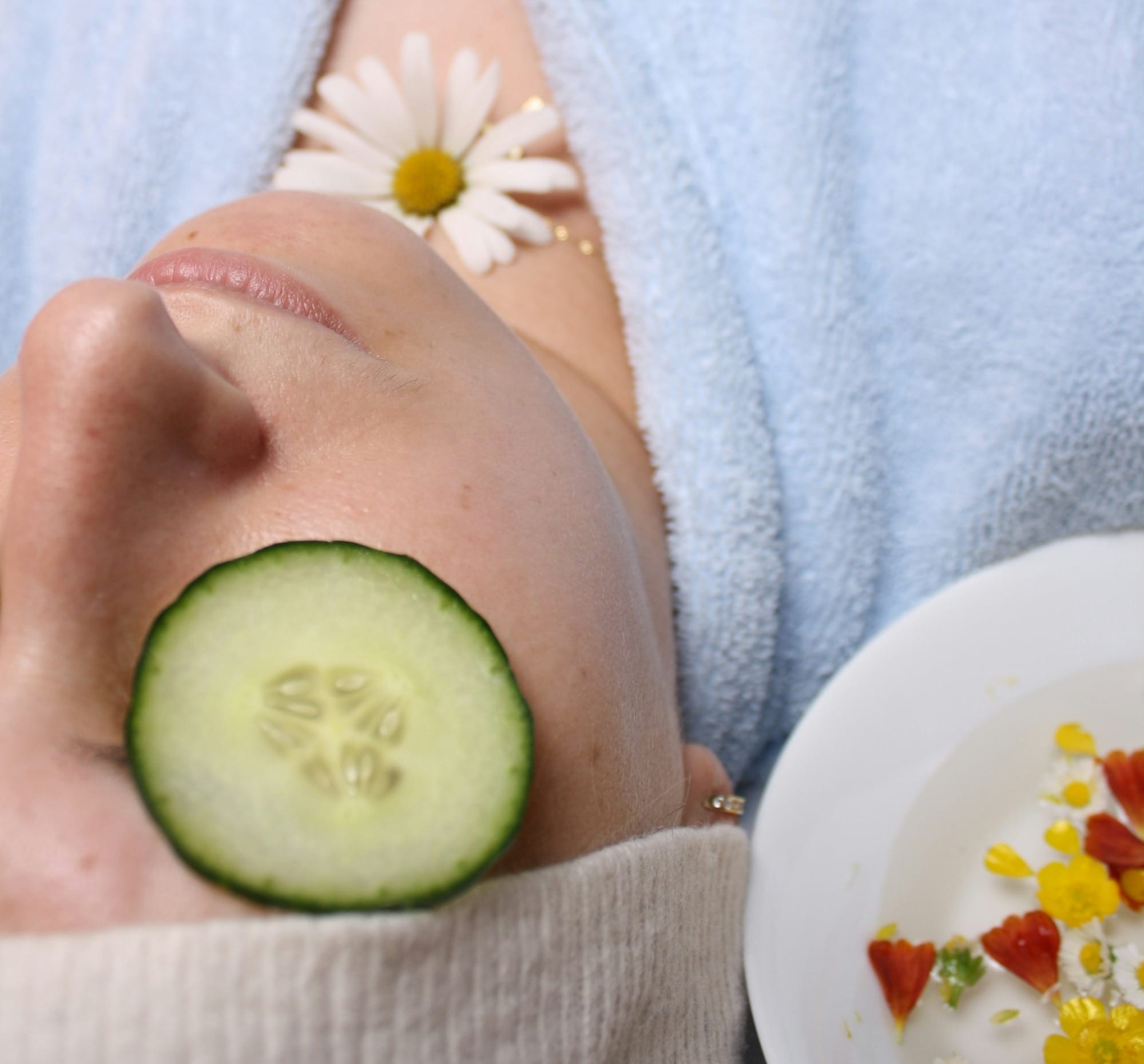 woman wearing blue robe lying with cucumber on eye - moisturizers for sensitive skin