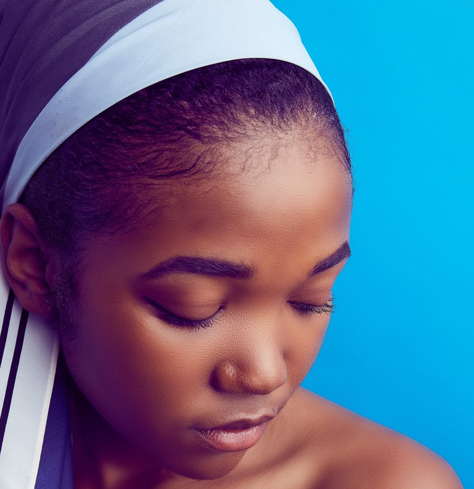 girl with scarf on her head against blue wall