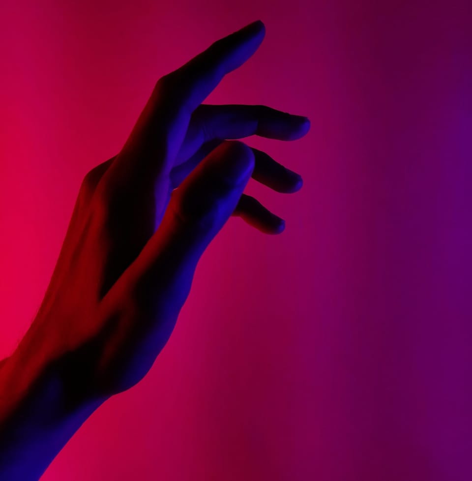 Person's hand held up in the air on neon pink background -  Best Hand Massagers