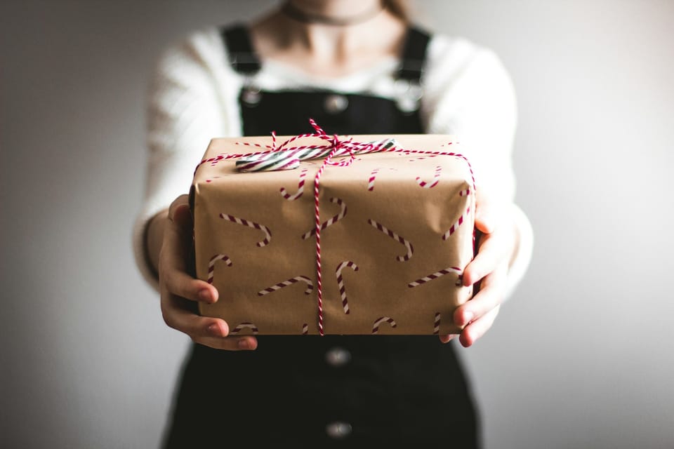 girl with black dress holding brown-paper wrapped gift