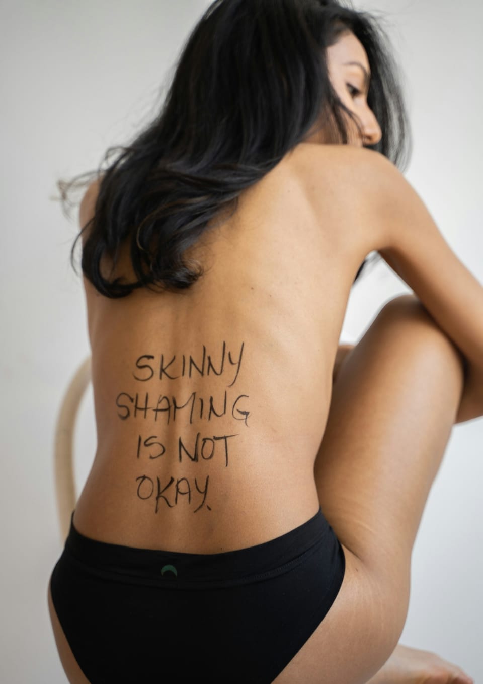 girl with black briefs with handwriting on her back "skinny shaming is not okay" - Best Weight Gain Supplements